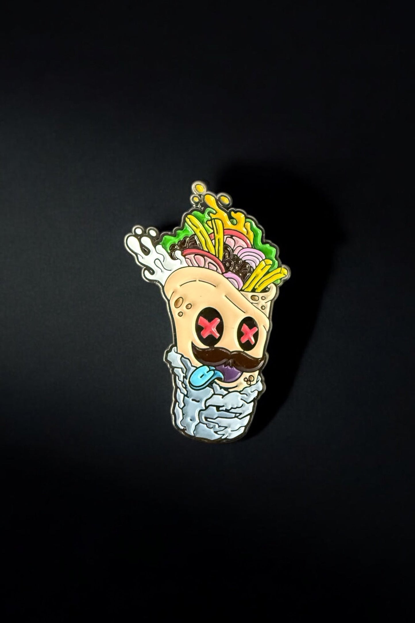 The Burrito Ball Marker by Crown Golf Designs features a vibrant cartoon burrito with red Xs for eyes, spilling tasty fillings and hot sauce, set against a plain black background.