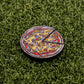 The Logie Joe's Golf Mexican Pizza "Slice" Premium Ball Marker is a round, cartoon-style pin with a removable slice, featuring yellow cheese and red-white toppings, shown on green artificial grass for a playful touch.