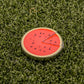 Logie Joe's Golf Watermelon "Slice" Premium Ball Marker features a red center, black seeds, green rind, and removable slice. This fun accessory resembles a watermelon on green turf—perfect for adding personality to your golf game.
