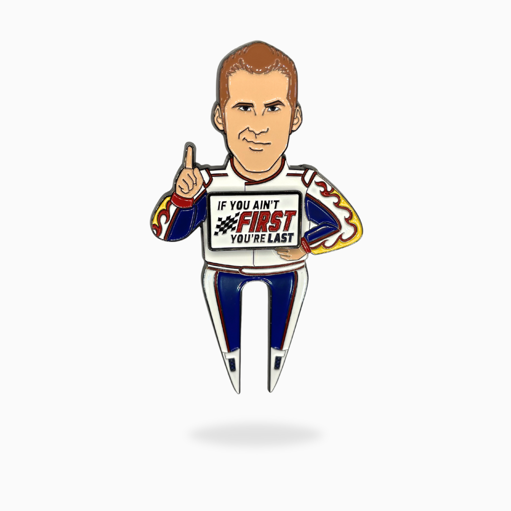 The Ricky Bobby Divot Tool by Pin Creatures features a cartoon race car driver in white and blue, holding up one finger with "If you ain't first, you're last" on his shirt—perfect for pairing with your favorite golf ball marker.