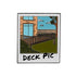 A drawing of a house with a deck, fence, grass, and tree appears Polaroid-style with "DECK PIC" on the border. The Deck Pic Ball Marker from Ballmarkers.com is perfect for sharing with playing partners.