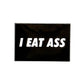 The Jogie Loes "I Eat A** Ball Marker" is a black, rectangular golf accessory with bold white text—perfect for sparking conversation on the green.