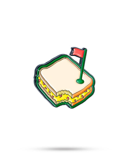 The Pimento Cheese Sandwich Ball Marker by Pins and Aces features a cartoon sandwich with a bite missing and a small red flag on top, isolated on white with a subtle shadow—an ideal addition to any Augusta golf accessory collection.