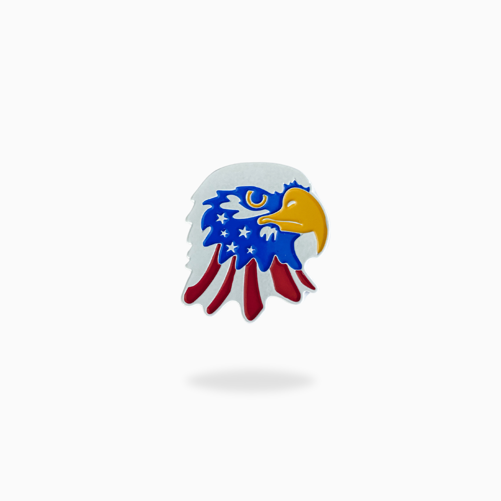 The Pin Creatures "American Bald Eagle" pin, featuring a flag-decorated eagle head with blue and white stars, red and white stripes, and a yellow beak, serves as a patriotic golf ball marker on a plain white background.