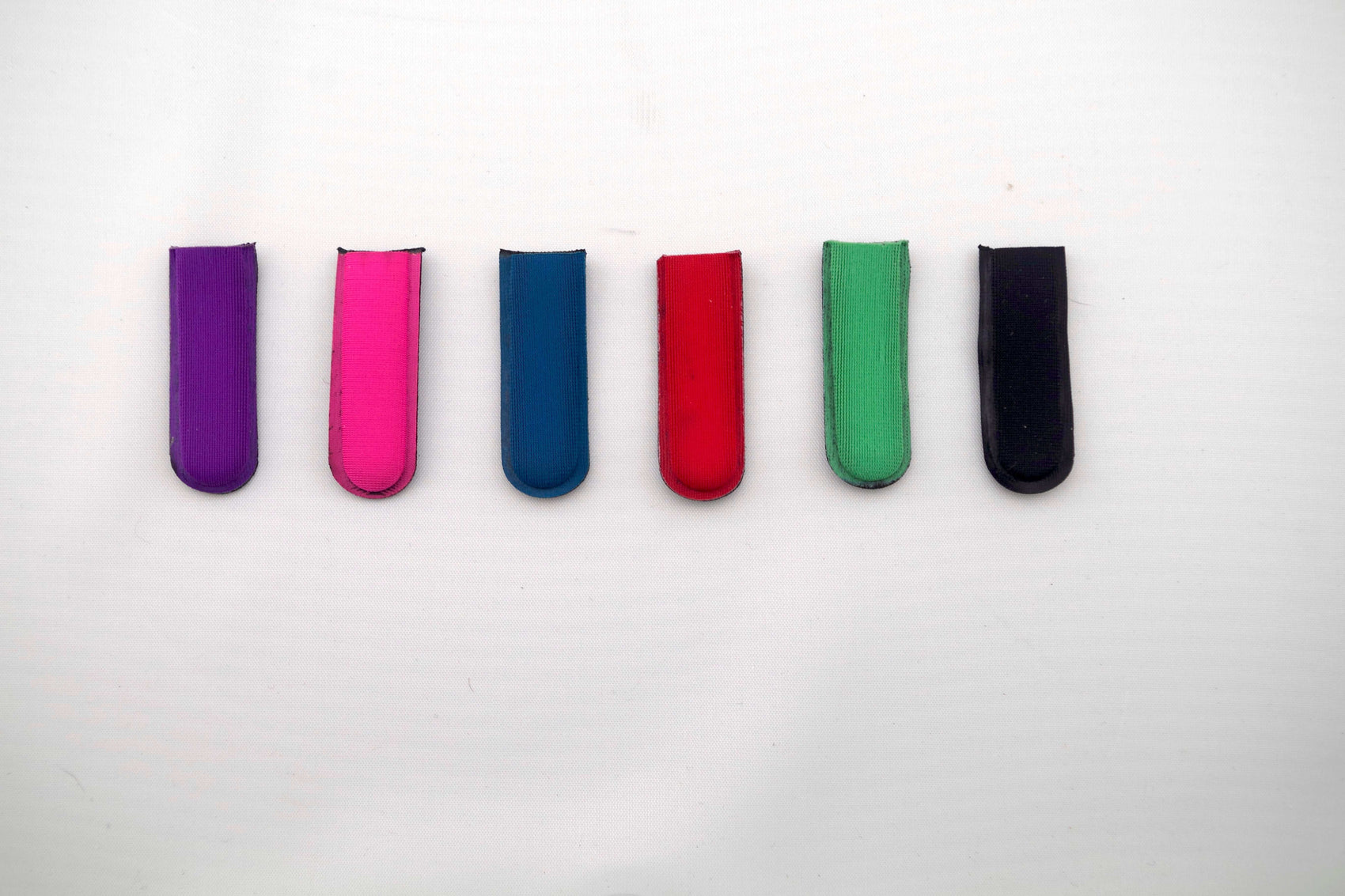 Six BYRD GOLF DIVOT CLYP fabric clips by The Byrd, LLC—purple, pink, blue, red, green, and black—are lined up on a white background. Low stock! Organize your golf gear and grab yours now before they're gone!.