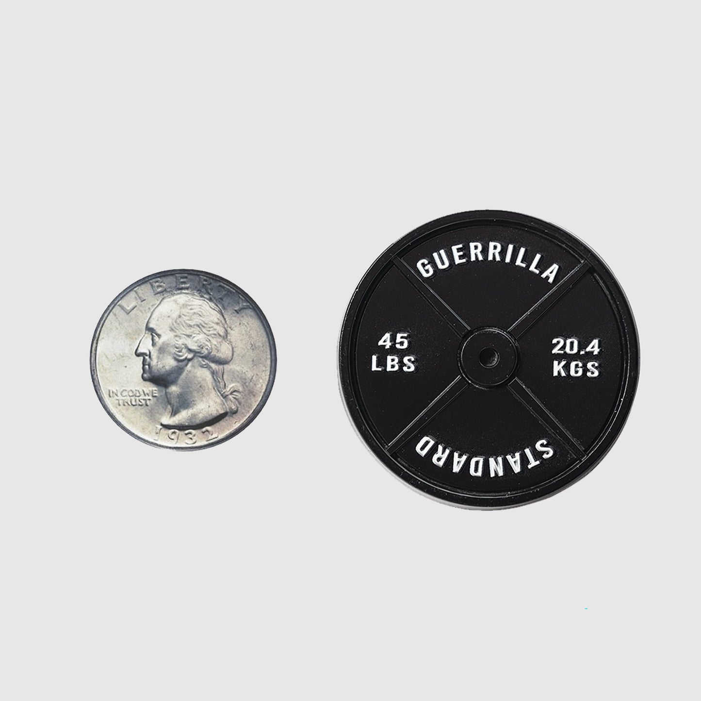 A U.S. quarter is placed next to the Guerrilla Golf 45lb Plate Ball Marker—a black, circular weight labeled "Guerrilla Standard"—shown on a plain white background, ideal for use as a heavy-duty gym ball marker or as a standard lifting accessory.