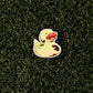 The Ducky Ball Marker by Shank it Golf, featuring a yellow duck with a red beak, is crafted from premium metal and rests on a grass-like surface—perfect as a fun magnetic ball marker for your game.