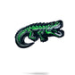 The Pins and Aces Crocodile Ball Marker features a green enamel crocodile with black and white details, its mouth open. Shown on a white background with a slight shadow, it's ideal for marking your golf ball on the course.