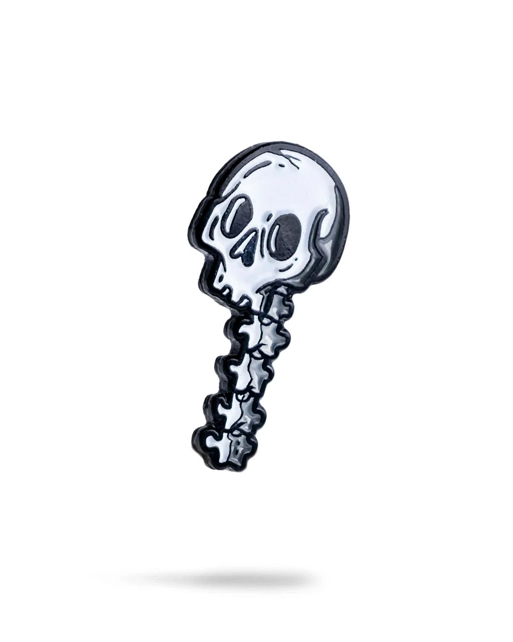 The Skeleton Ball Marker by Pins and Aces is a cartoon-style enamel pin showing a white skull with big black eyes and a short curved spine, crafted with stainless steel accents on a plain white background.