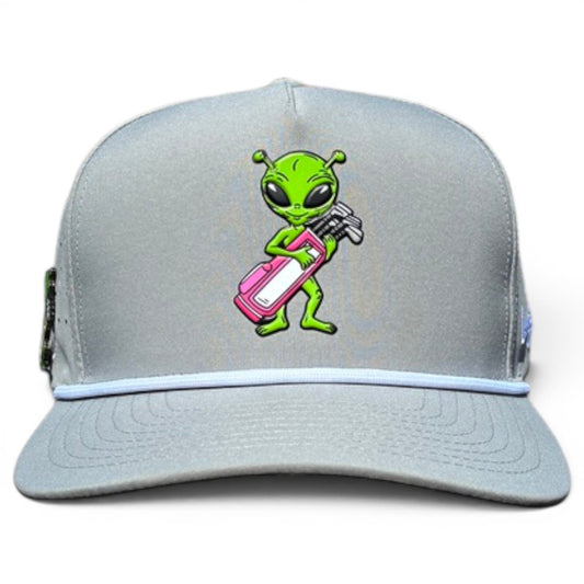 The Logie Joe's Golf Alien Caddy Golf Hat is a light gray snapback cap with a cartoon green alien holding a pink and white golf bag, curved bill, white accent line, and built-in magnetic ball marker holder plus marker included.