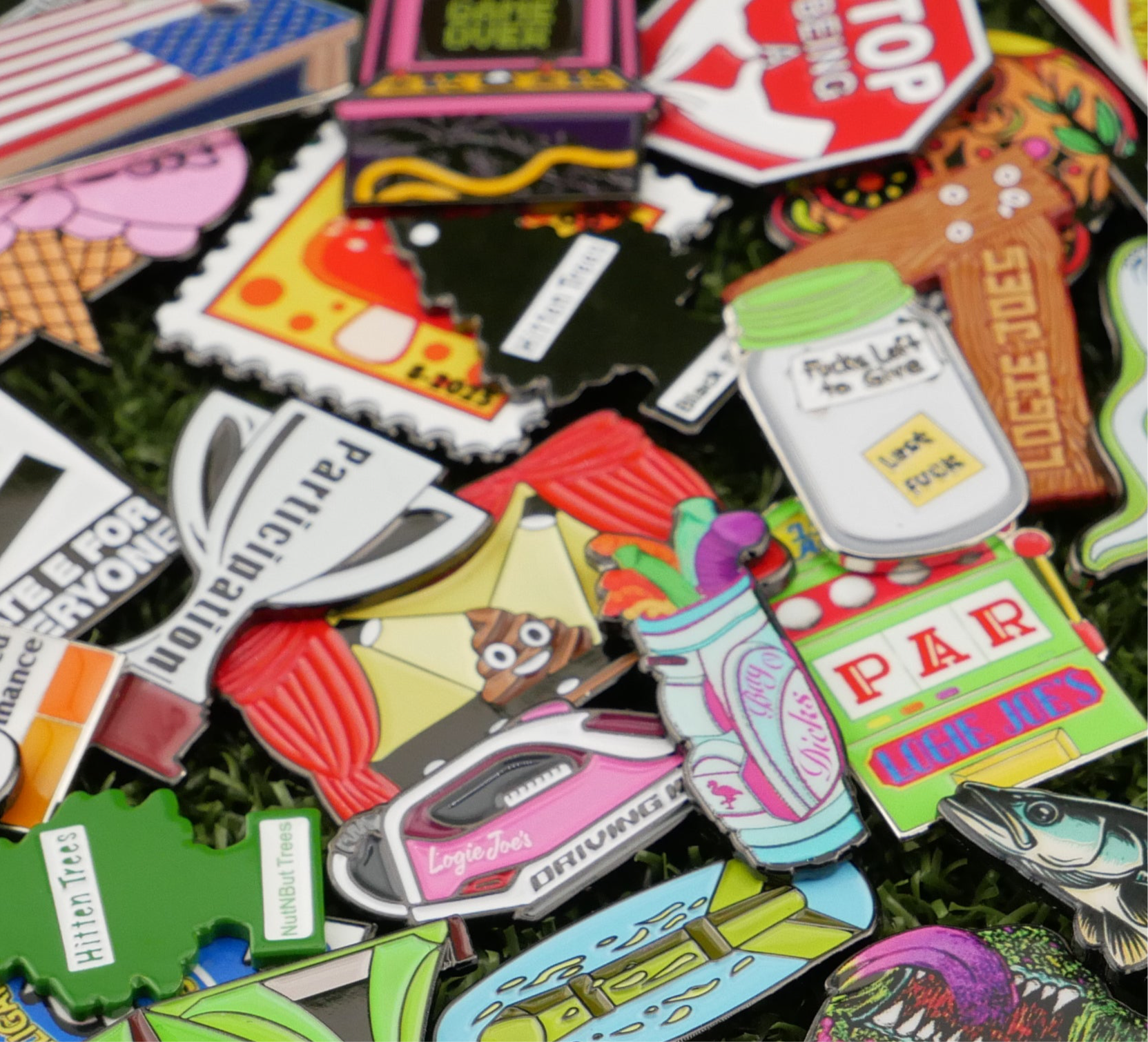 A close-up of vibrant enamel pins, including a golf bag and pizza slice, scattered on grass highlights the Custom Mystery Ball Marker Pack—unique golf ball markers that make standout premium accessories.
