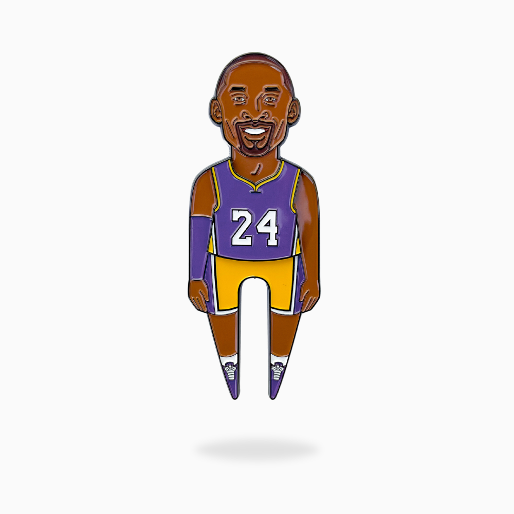 The MAMBA Divot Tool by Pin Creatures features a cartoon enamel pin of a smiling basketball player in a #24 purple and gold jersey—perfect for sports fans or as a unique ball marker for your golf accessories.