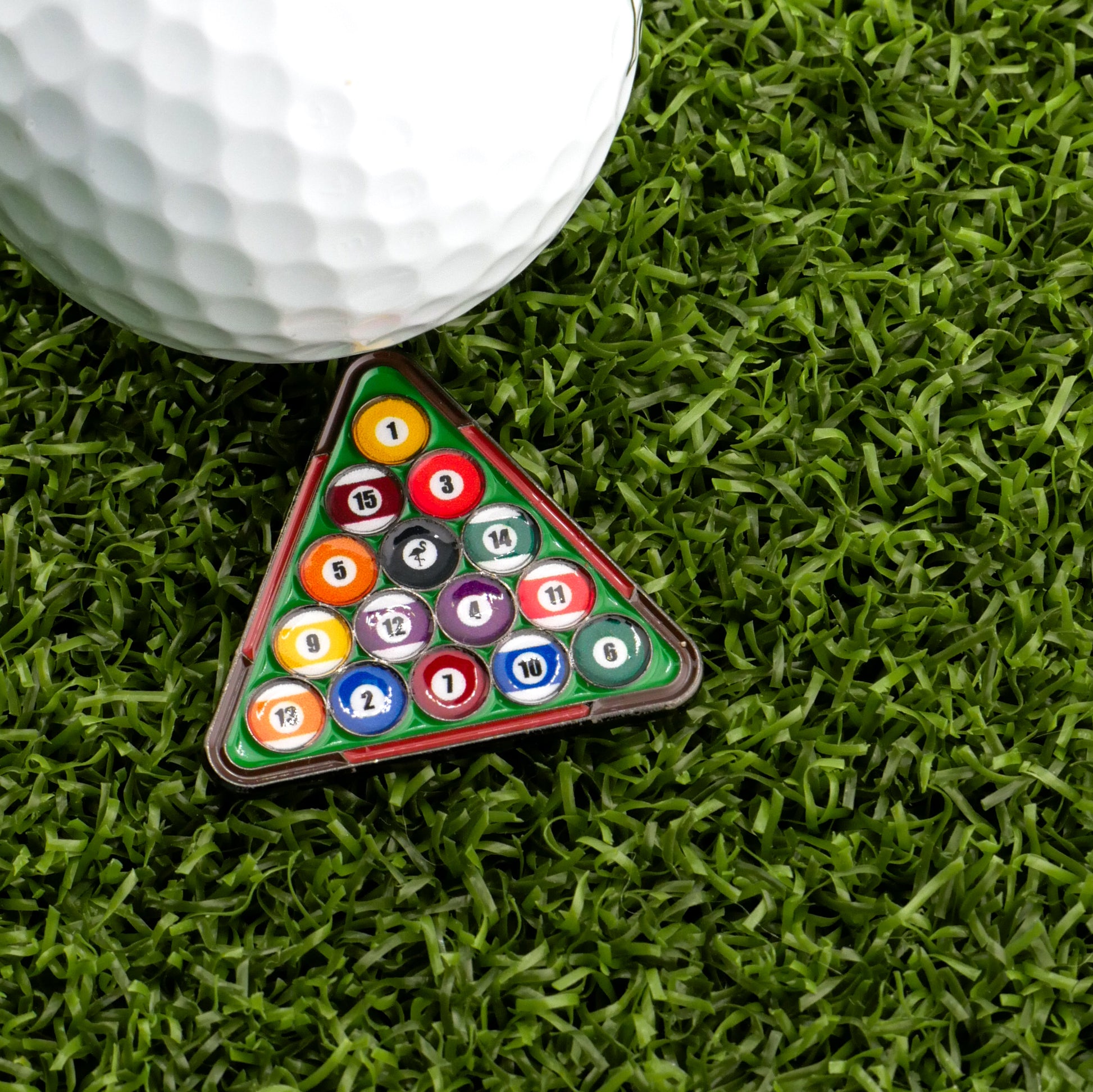 The Logie Joe's Golf 8-Ball Pool Rack Ball Marker pairs a large golf ball with a mini pool rack, making unique premium markers displayed on green artificial grass.
