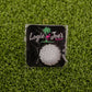 The Logie Joe’s Golf 8-Bit Golf Ball—a pixelated, round white golf ball—appears on green artificial grass in its branded packaging.