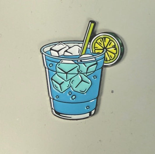 A drawing featured on the Water Hazard Ball Marker by Ballmarkers.com shows a blue drink in a glass filled with ice cubes, topped with a yellow straw and a lime slice on the rim—capturing the refreshing feeling of cooling down after conquering a water hazard on the golf course.