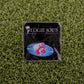 A small pin from Logie Joe's Golf features a pink axolotl in a blue oval, attached to a black card with the brand name and palm tree logo—ideal for fans of unique golf accessories or golf ball markers.