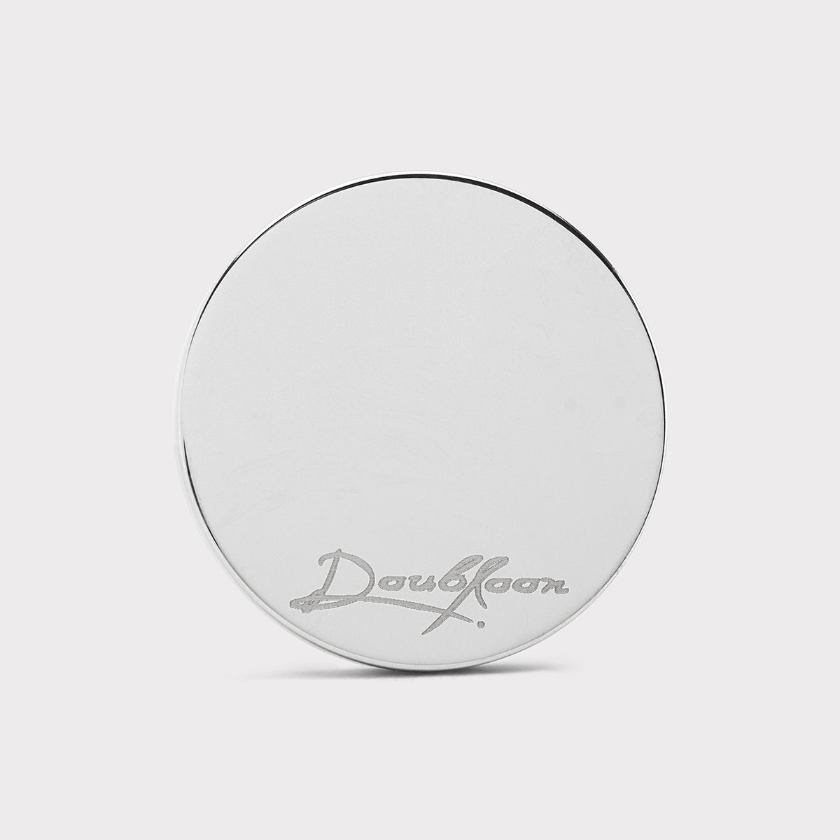 A round, silver-colored metal object called The Venom by Doubloon, crafted from lightweight titanium with "Doubloon" engraved in script near the bottom, set against a plain light gray background.