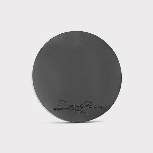 A round, flat, black bar from Doubloon called The Omen Classic Antique stands upright against a plain light background, featuring the brand name engraved in cursive near the bottom and evoking the style of a classic doubloon.