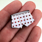 A hand holds the Heart Boxers Ball Marker by Pins and Aces, a magnetic pin shaped like white boxer shorts with a red heart pattern.