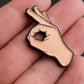 A close-up shows a hand holding the Pins and Aces OK Hand Ball Marker, an enamel golf marker shaped like a hand making the OK gesture—a unique premium accessory for golfers.
