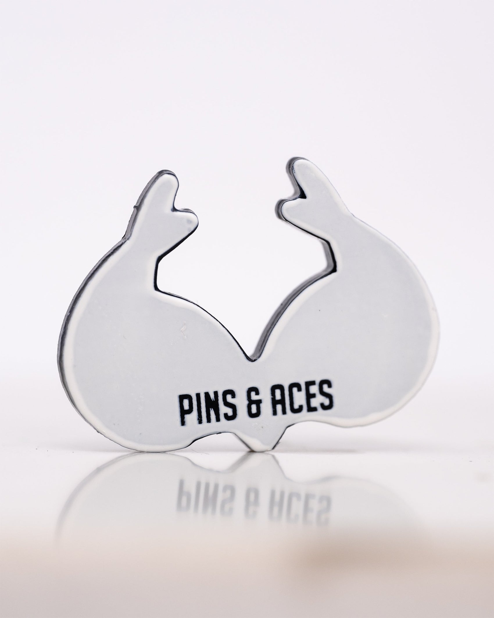 A ball marker shaped like real tree antlers with the text Pins and Aces printed on it, set against a plain white background.