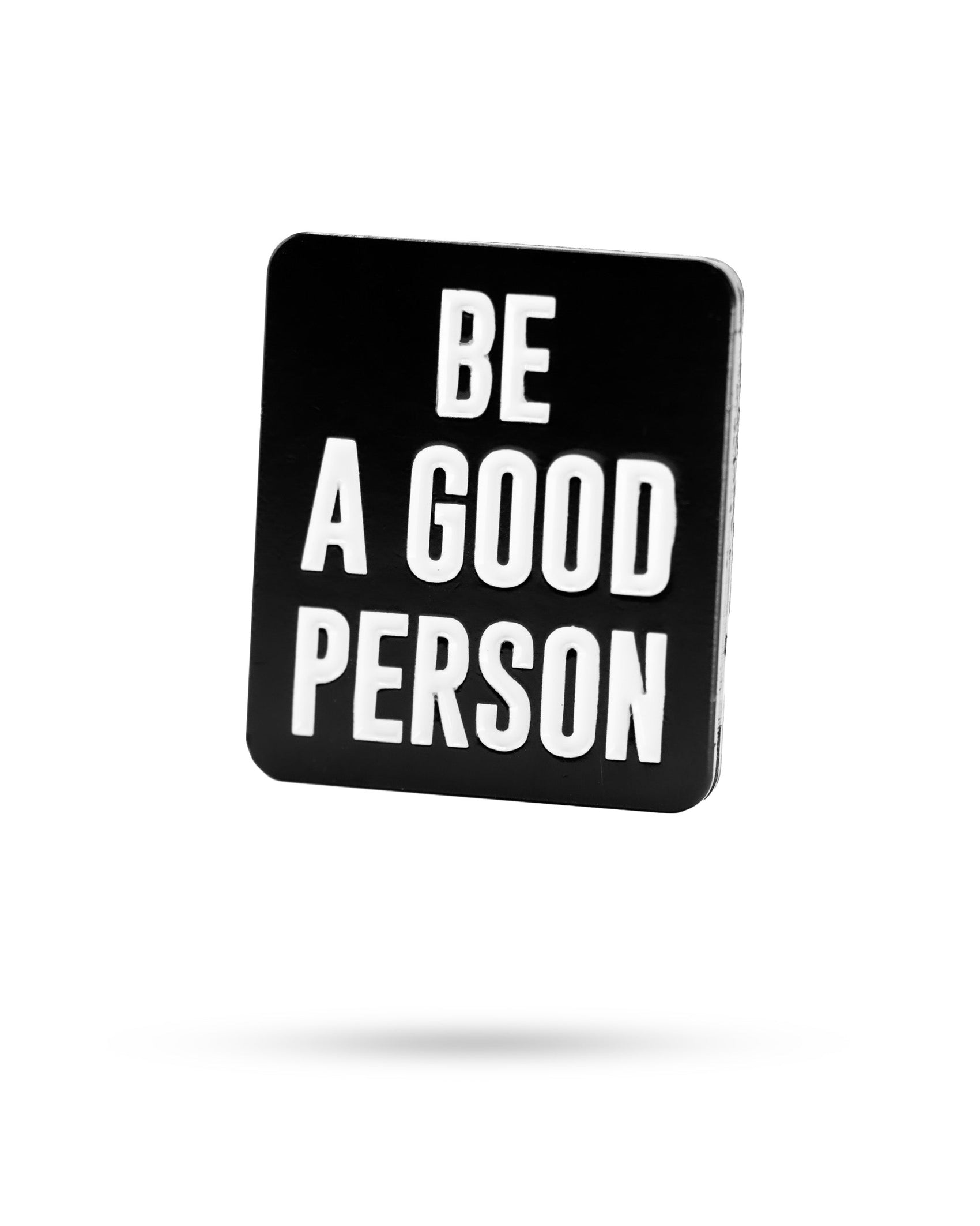 The Pins and Aces "Be A Good Person" ball marker features bold white text on a black rectangle—an inspiring accessory for your next round.