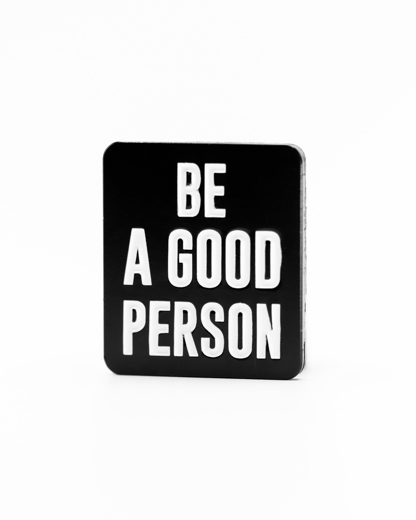 The Be A Good Person - Ball Marker by Pins and Aces features bold white letters on a black rectangular marker, standing out with a simple design similar to their signature style.