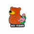 A cartoon brown bear and pink flamingo stand side by side above "BEST FRIENDS" in bold white letters on black—a fun golf ball marker design from Logie Joe&