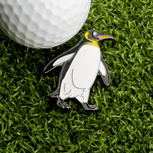 The Penguin Ball Marker from Ballmarkers.com rests on vibrant artificial grass beside a white golf ball, creating a charming animal-themed marker that’s among the most unique golf accessories—a fun and playful addition to any game.