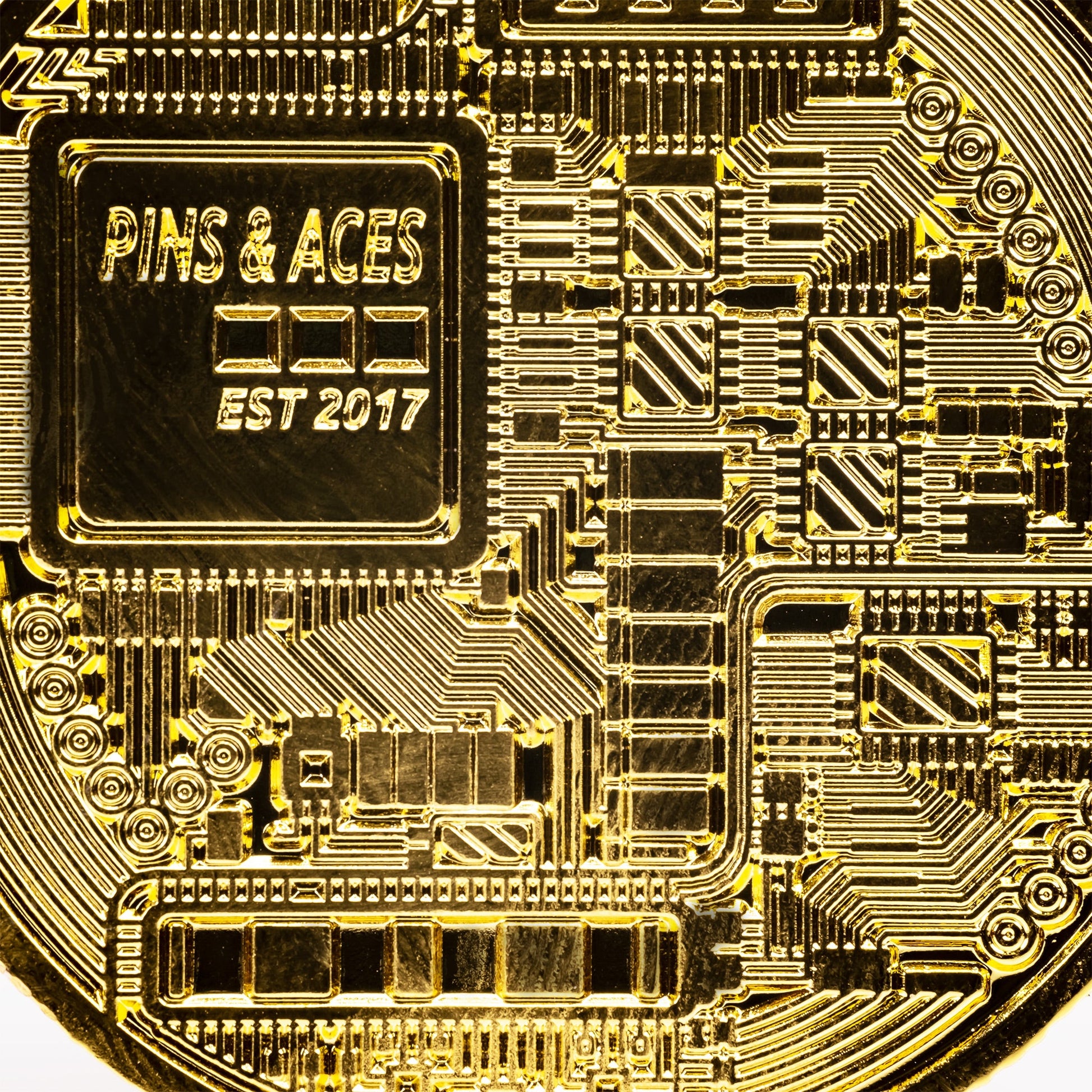 A close-up of the Pins and Aces Bitcoin Ball Marker—a gold coin with circuit patterns and chrome finish, engraved with PINS & ACES EST 2017—ideal as a unique golf ball marker.