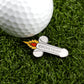 A golf ball on artificial grass sits beside Logie Joe's Golf Cocketship—a cartoon rocket-shaped, cheeky ball marker that adds playful humor to your game with its unique phallic design.