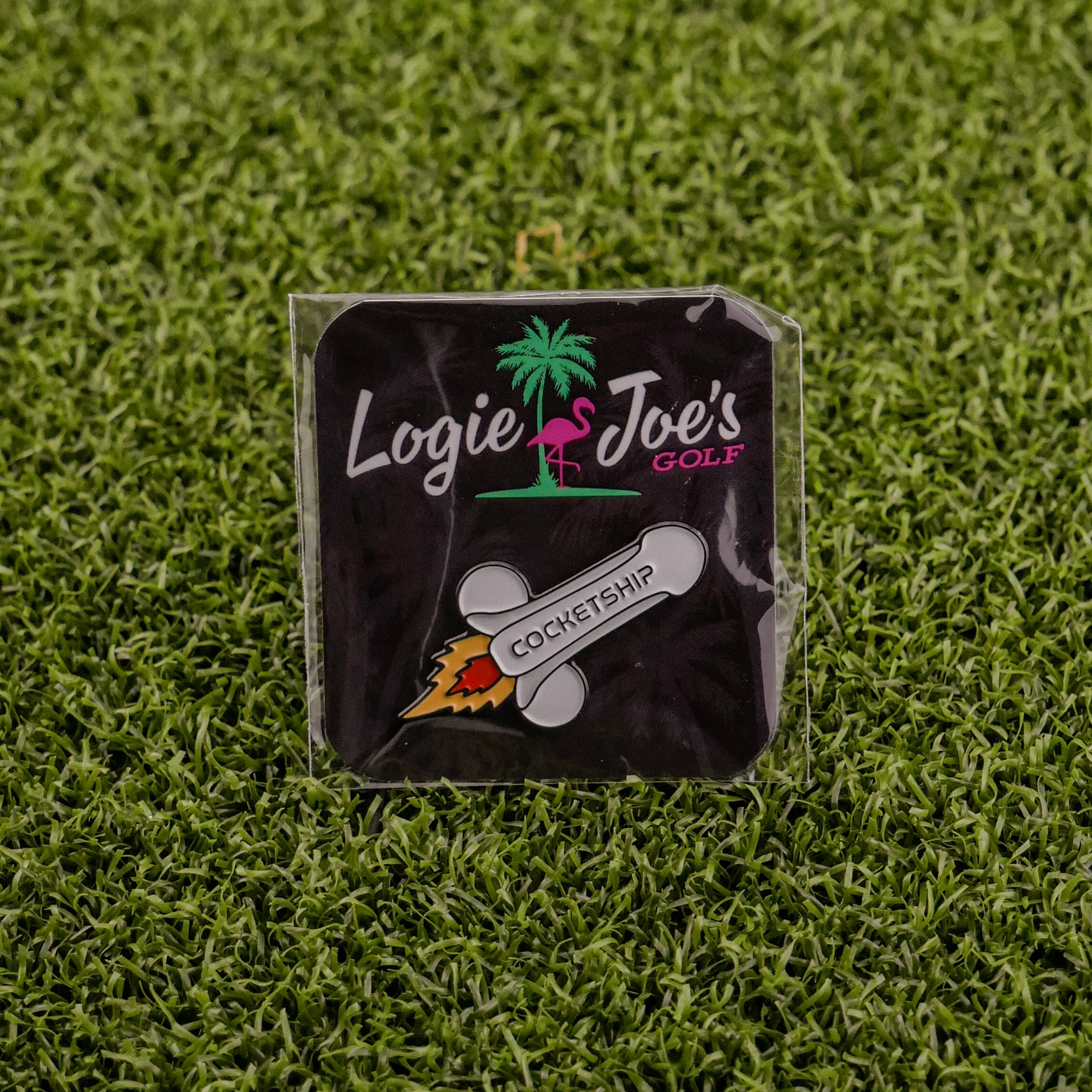 Add humor to your game with the Cocketship pin from Logie Joe’s Golf—shaped like a rocket and packaged with a flamingo and palm tree motif atop artificial grass.