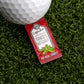 A golf ball rests on artificial grass next to the Logie Joe's Golf Tomato Ketchup Sauce Packet Ball Marker, featuring a pin with the phrase "We Real Fancy.