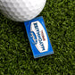 A blue and white Mayonnaise Sauce Packet Ball Marker from Logie Joe's Golf sits on green artificial grass next to a white golf ball.