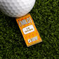 A golf ball and a Mild Taco Sauce Packet Ball Marker by Logie Joe's Golf rest on artificial grass—making a funny gift for golfers who love mild sauce.