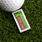 The Logie Joe's Golf Sweet Relish Sauce Packet Ball Marker playfully mimics a relish packet with its colorful rectangular design and “Sweet Relief” print, shown beside a golf ball and green pin on artificial grass.