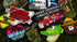 A vibrant selection of Custom ball marker enamel pins by Custom, featuring trucks, alligators, cartoon characters, and logos, displayed on a textured green background.