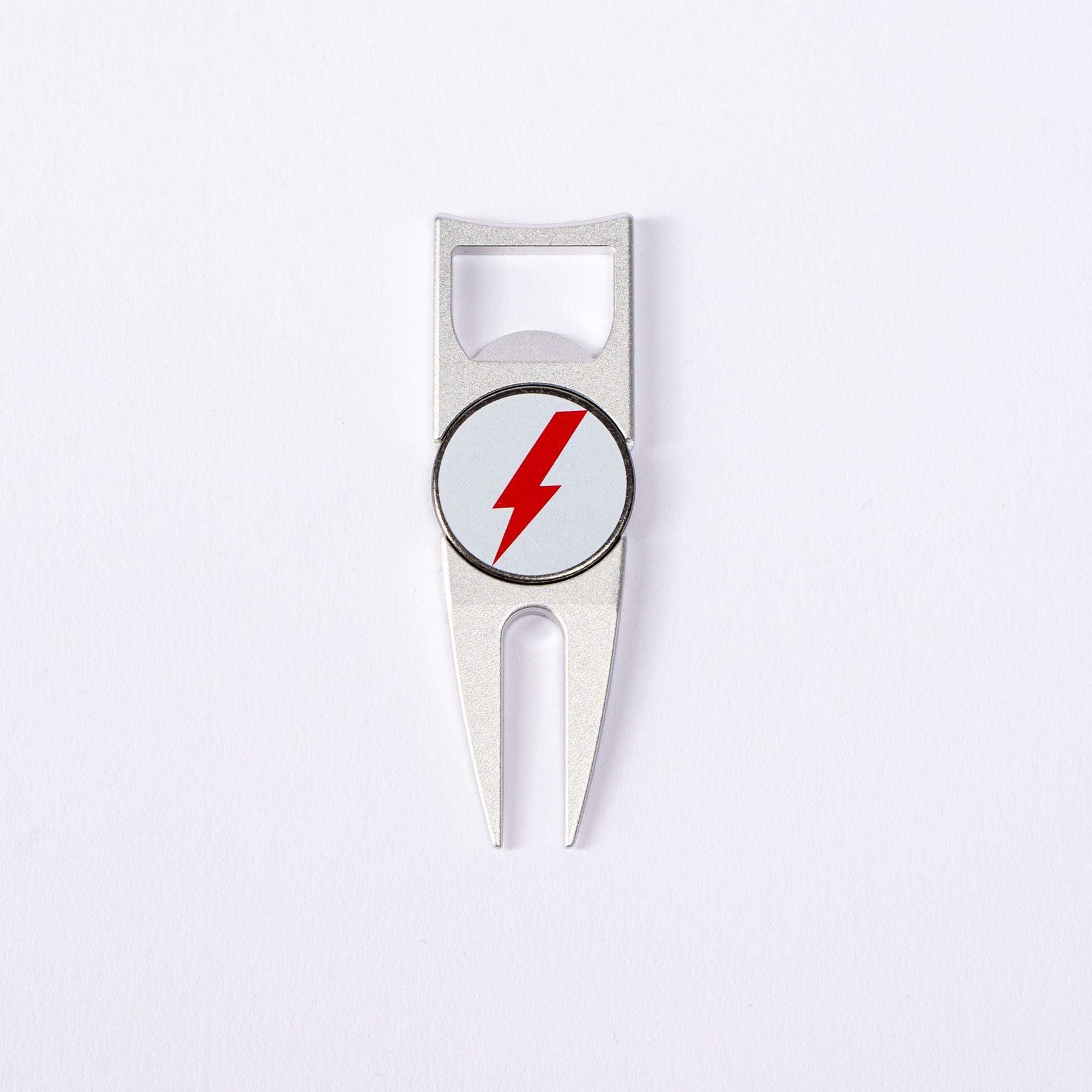 The BYRD DIVOT TOOL - 4 in 1 by The Byrd, LLC is a silver golf divot tool with a red lightning bolt in a white circle on its round center and includes a ball marker holder, shown on a plain white background.