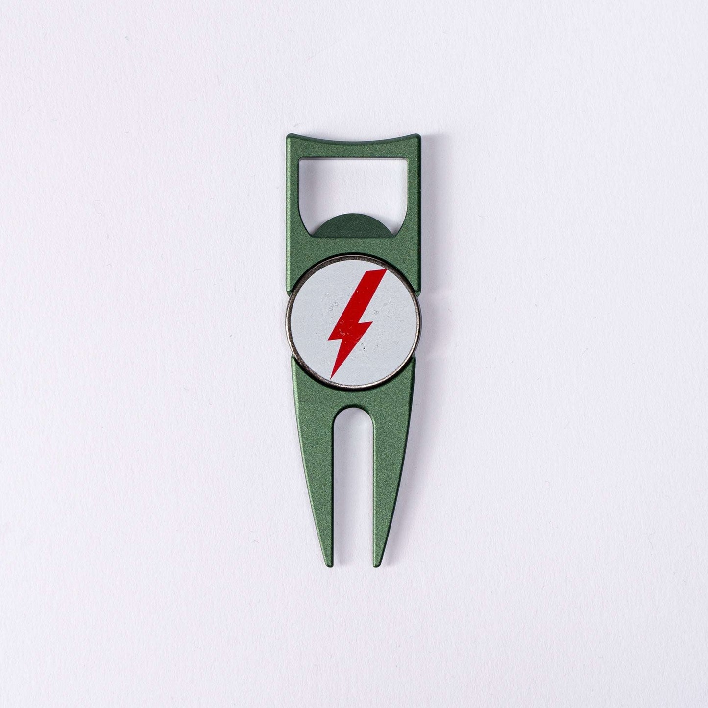 The BYRD DIVOT TOOL - 4 in 1 by The Byrd, LLC is a green metal divot tool and ball marker holder with a circular white emblem featuring a red lightning bolt, shown on a plain white background.
