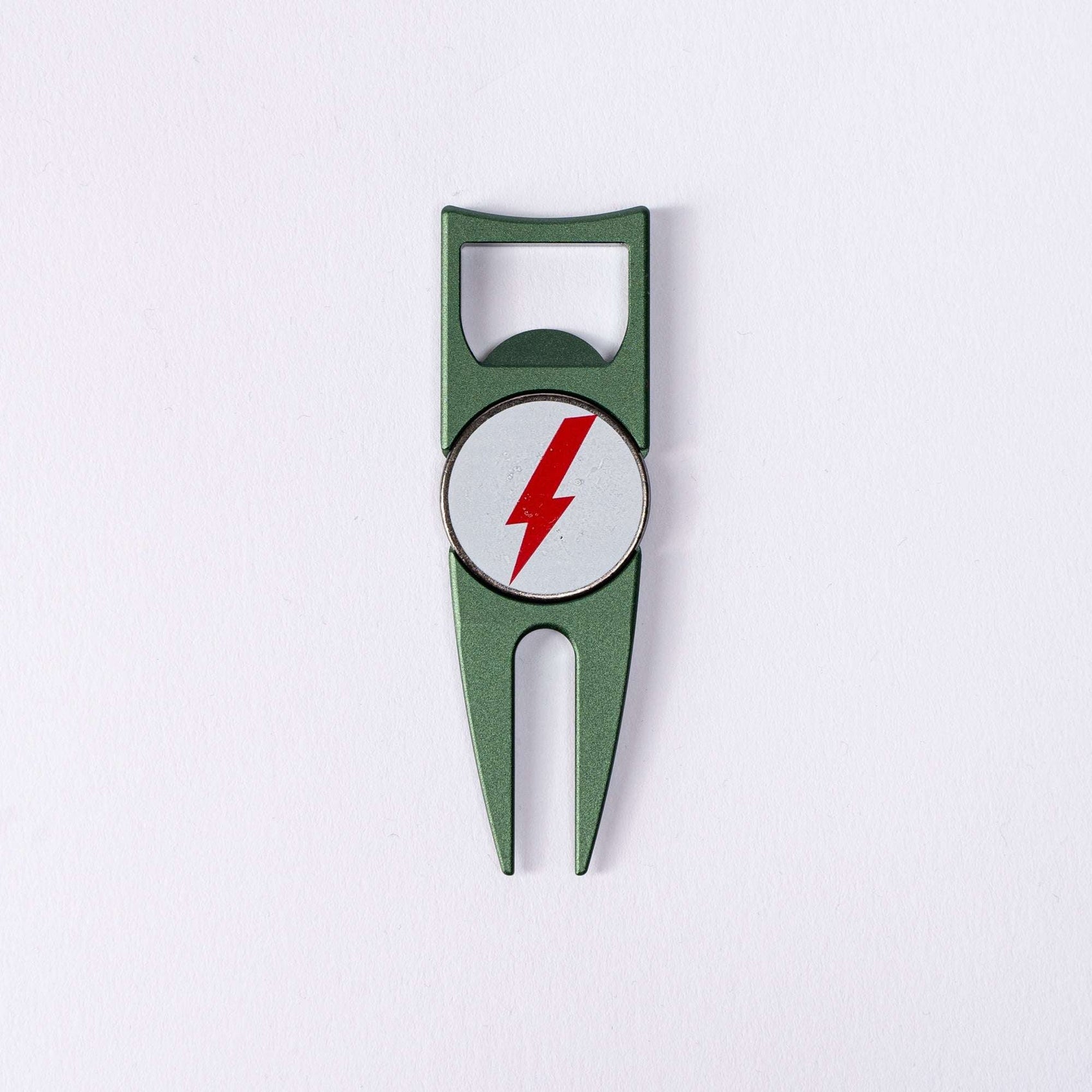 The BYRD DIVOT TOOL - 4 in 1 by The Byrd, LLC is a green metal divot tool and ball marker holder with a circular white emblem featuring a red lightning bolt, shown on a plain white background.