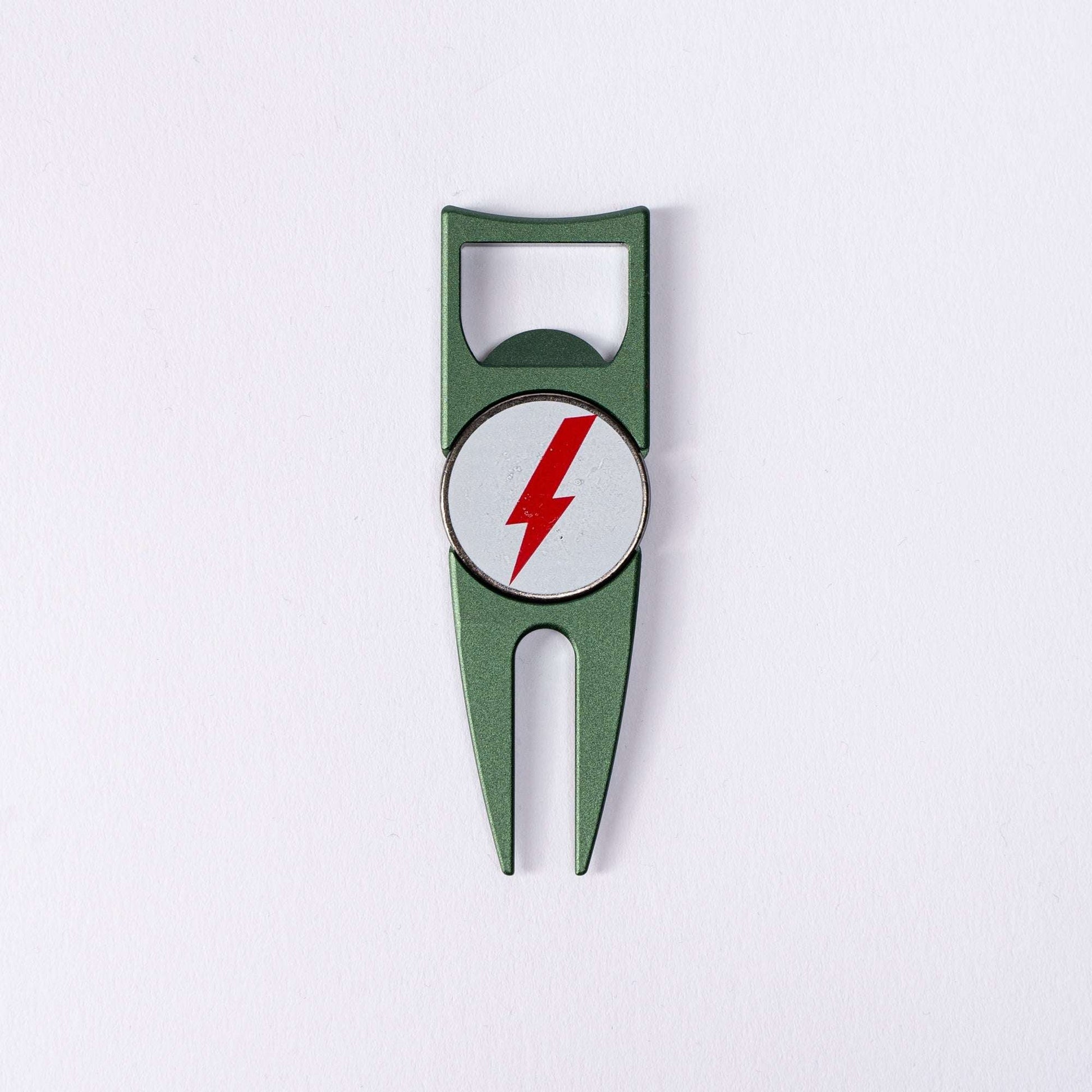The BYRD DIVOT TOOL - 4 in 1 by The Byrd, LLC is a green metal divot tool and ball marker holder with a circular white emblem featuring a red lightning bolt, shown on a plain white background.