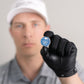 A person in a white cap and black glove holds Doubloon’s The Silver Omen Antique, Color Edition golf ball marker with a blue skull design, focusing on the marker while their face is blurred in the background.