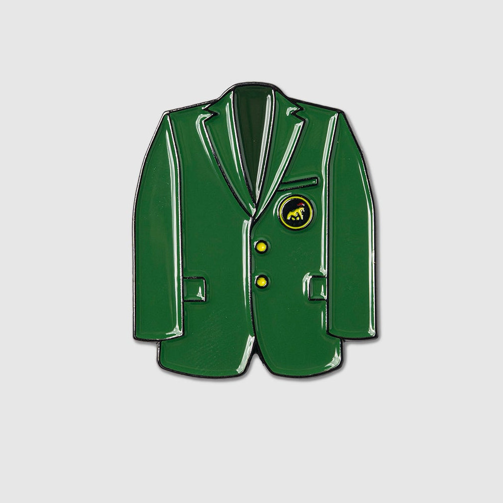 The Green Coat Ball Marker by Guerrilla Golf is shaped like a green sports coat with yellow buttons and a circular emblem on the chest, resembling a blazer and set against a plain light gray background.