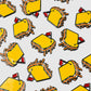 Several Guerrilla Golf Pimento Ball Markers—yellow rectangles with orange edges and a small red flag—are arranged on a white background, resembling artfully decorated treats for a playful, food-inspired effect.