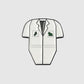 A Guerrilla Golf Caddy Bib Ball Marker pin shaped like a white short-sleeve lab coat, featuring green symbols on the chest pockets, reminiscent of a fun novelty marker and set against a plain gray background.