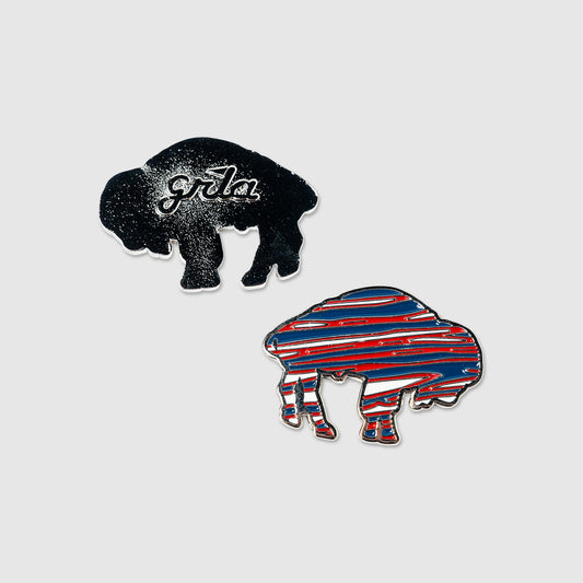 Show off your team spirit on the course with the Guerrilla Golf RWB Buffalo Ball Marker set. This pair of buffalo-shaped pins includes one in classic black featuring "gr8a," and another styled with bold red, white, and blue horizontal stripes—just like a traditional Buffalo ball marker. Both pins are displayed against a clean light gray background.