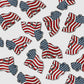 Multiple American Flag Gorilla Ball Markers from Guerrilla Golf, each featuring a raised fist design with the iconic flag pattern, are scattered across a white background—a bold nod to American style and the spirit of golf putting.