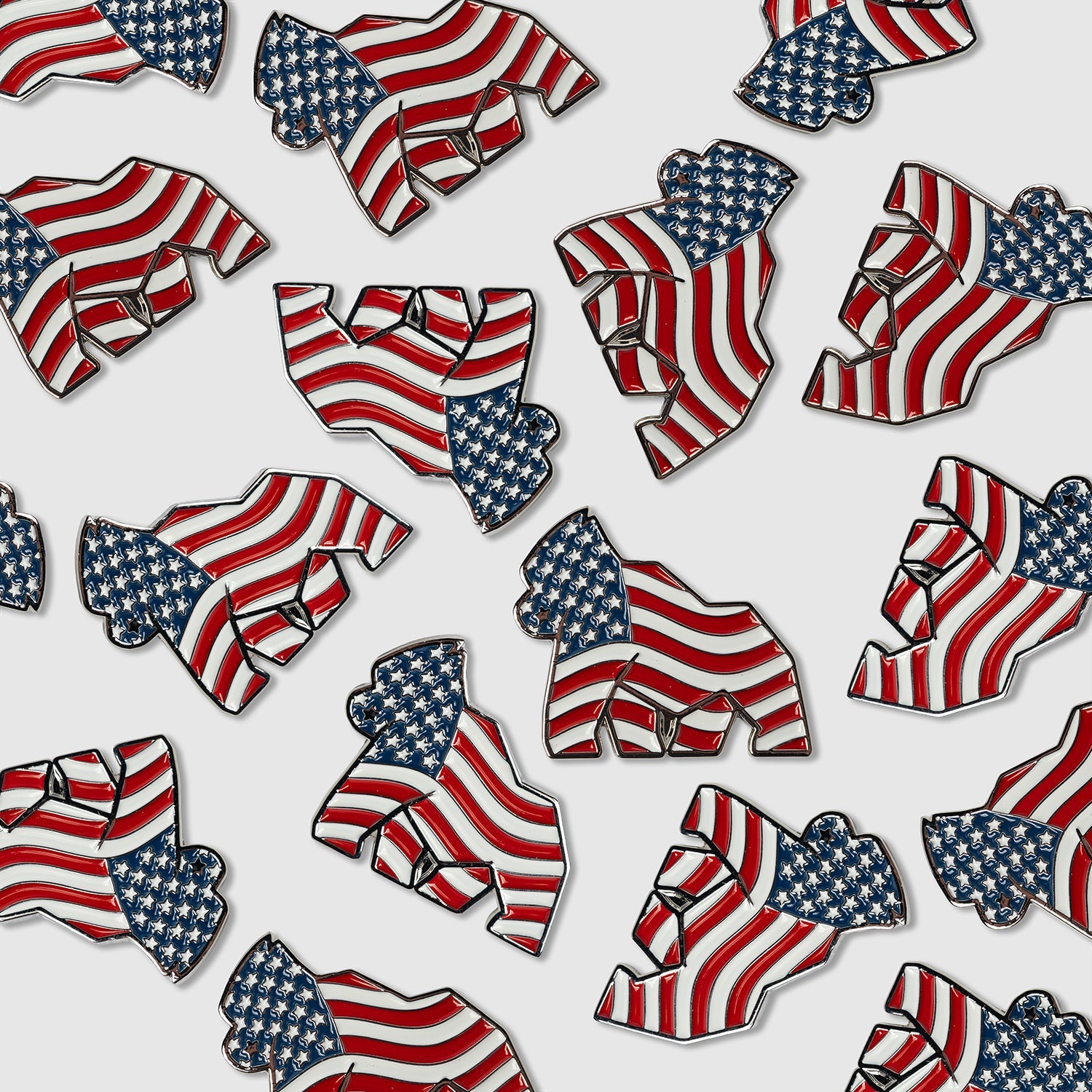 Multiple American Flag Gorilla Ball Markers from Guerrilla Golf, each featuring a raised fist design with the iconic flag pattern, are scattered across a white background—a bold nod to American style and the spirit of golf putting.