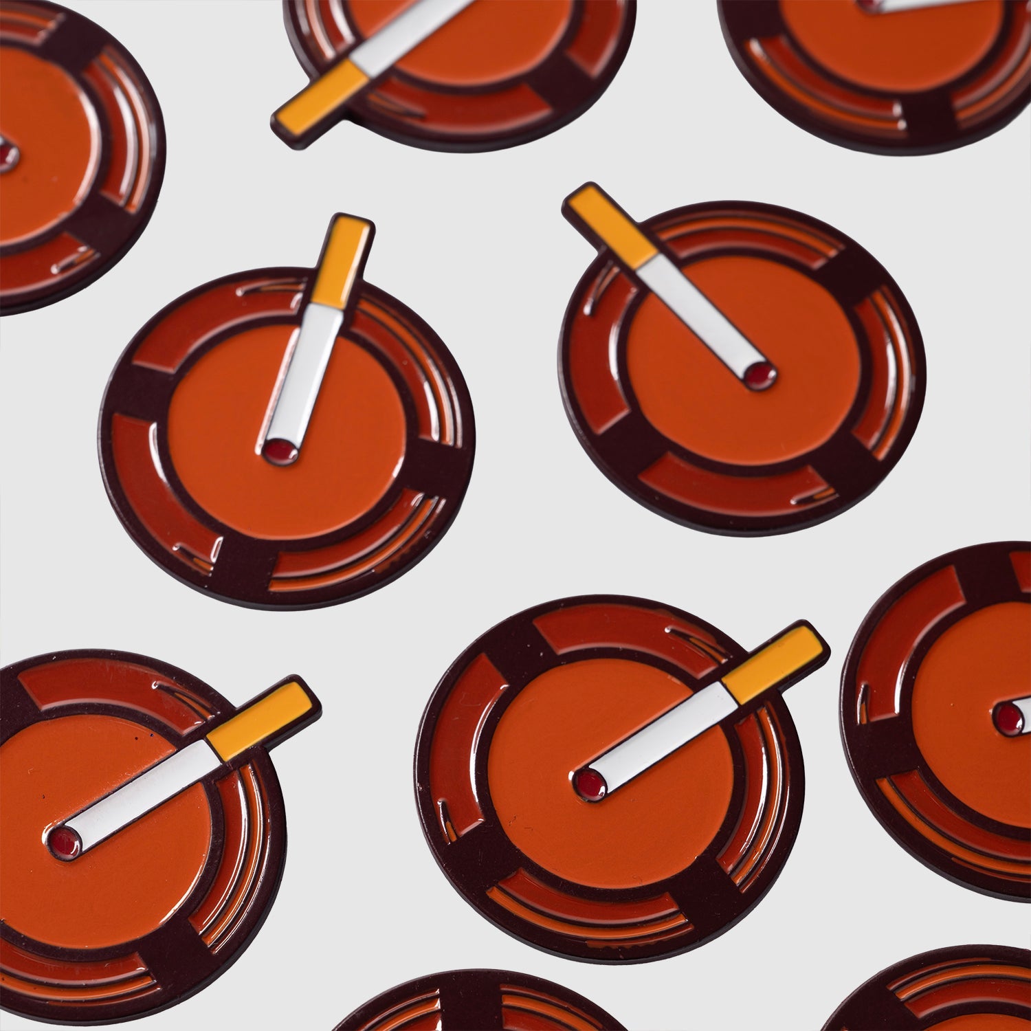 A pattern featuring Guerrilla Golf's Retro Ashtray Ball Markers—each with a lit cigarette detail—arranged on a white background for an unexpected design that makes a unique and funny golf gift.