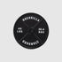 A black 45lb Plate Ball Marker by Guerrilla Golf, featuring "GUERRILLA STANDARD" along with weight markings of 45 LBS and 20.4 KGS in crisp white text against a light gray backdrop—its robust design evokes the industrial strength of a manhole cover.